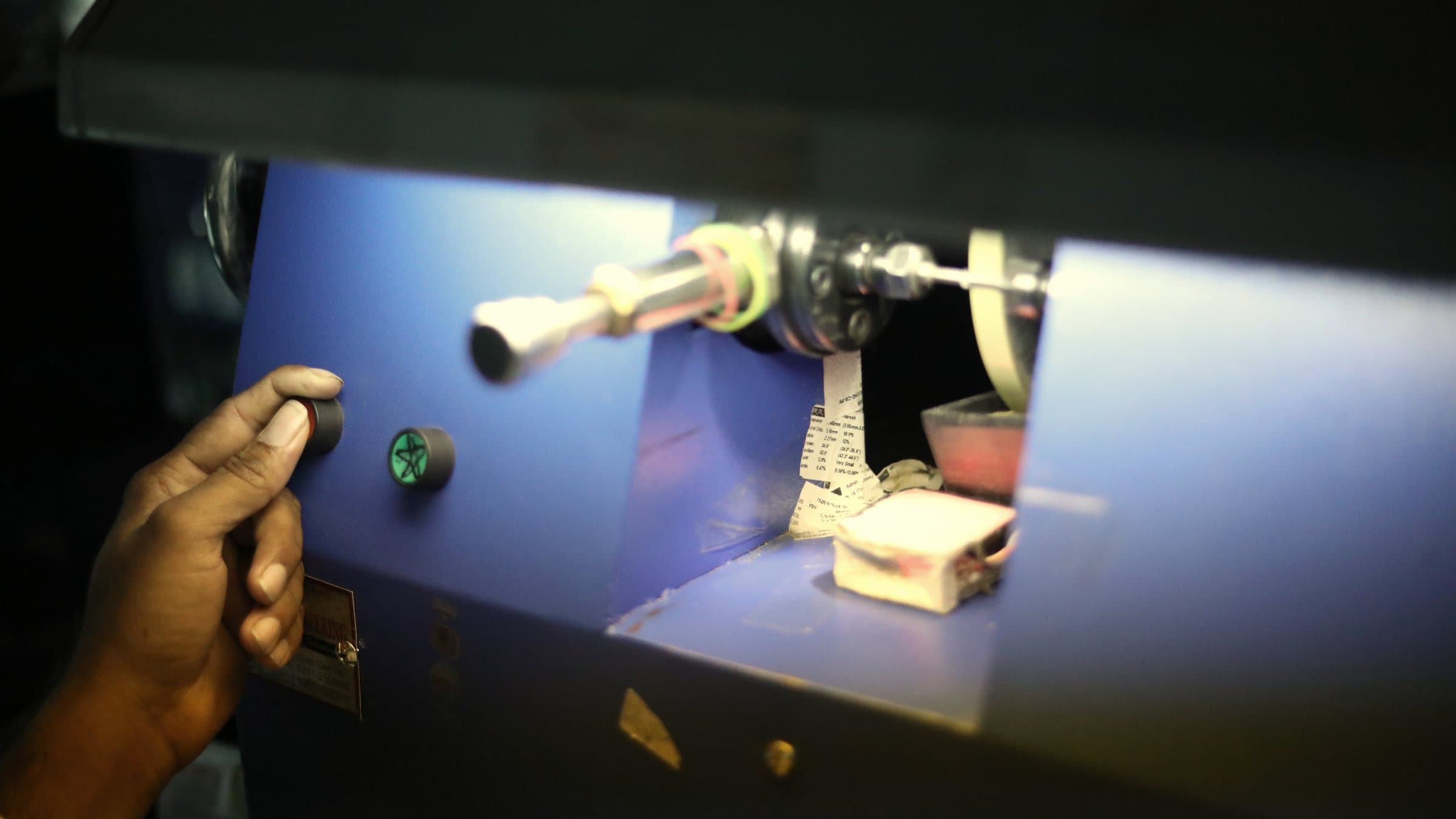 A hand at the controls of a blue polishing machine